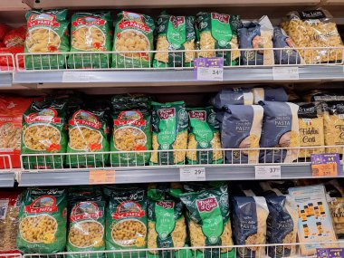 LVIV, UKRAINE - 30 Ağustos 2024: Renkli ve farklı şekillerde makarna paketleri sergilenen, akşam yemeği seçeneklerini seçen müşterilere hizmet veren iyi örgütlenmiş bir market rafı.