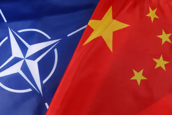 stock image LVIV, UKRAINE - September 03, 2024: The flags of NATO and China are displayed together, representing the complex dynamics of global politics and international relations between Western alliances and China.