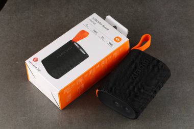 LVIV, UKRAINE - 09 Eylül 2024: Portatif bir hoparlör desenli bir yüzeyde ambalajının yanına yerleştirilir, tasarımı vurgulanır