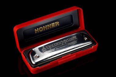 LVIV, UKRAINE - 13 Ocak 2025: Bir mızıka parlak kırmızı bir çantada dinleniyor, enstrümanın zarif tasarımı ve zanaatkarlığını gözler önüne seriyor, müzik severler ve sanatçılar için mükemmel.