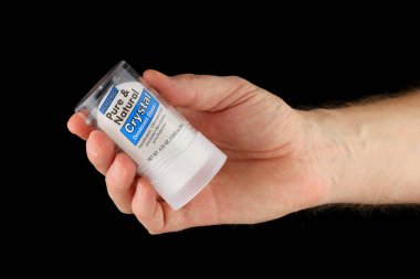 LVIV, UKRAINE - 13 Ocak 2025: Bir el ambalajını renklendirirken bir çubuk deodorantı tutuyor. Ürün, ortak bir kişisel bakım ürününü temsil ediyor..