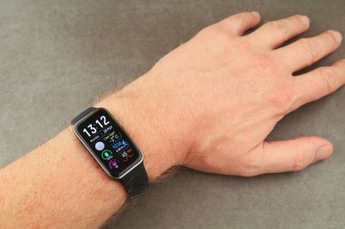 LVIV, UKRAINE - 28 Nisan 2025: Huawei Band 9 Akıllı bir hareketle süslenmiş bir bilek, teknolojinin günlük hayata entegrasyonunu yansıtan sağlık istatistikleriyle birlikte zamanı gösterir.