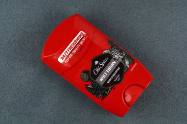 LVIV, UKRAINE - 26 Mayıs 2025: Vücut deodorantının kırmızı kabı yumuşak gri bir yüzeye karşı doğa temalı bir tasarım ve koku ayrıntıları sergiliyor.