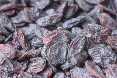 Kurumuş siyah kuru üzümler, buruşuk dokularını ve koyu renklerini sergiliyorlar..