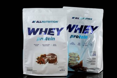 LVIV, UKRAINE - September 30, 2025: Two packs of whey protein sit on a black surface, showcasing their flavors and benefits.