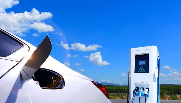 Mavi gökyüzü ve bulutlu arka planı olan elektrikli araba şarj istasyonu. EV araba konsepti. elektrikli araç, çevre dostu, gelecekteki teknoloji ve temiz enerji, alternatif enerji.