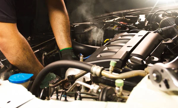 Otomobil tamircisi oto tamir servisinde çalışıyor. Araba tamircisi araba motoru üzerinde çalışıyor..