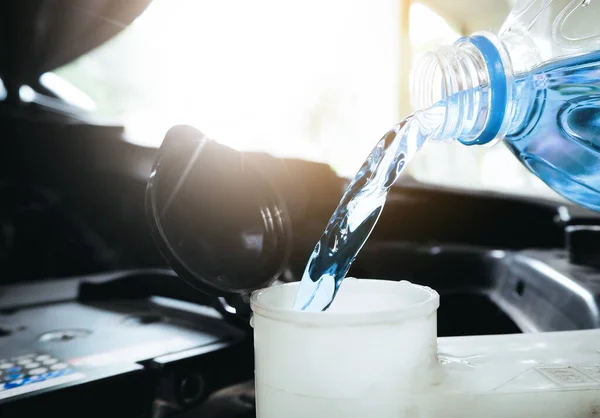 stock image Close up of a bottle of water being poured into a windshield washer tank.