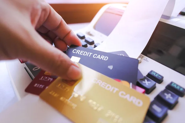 Hand holding credit card with printing calculator on table, black credit card mock in human hand, The concept of financial operations and credit card in the office.