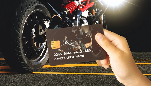 Credit or debit card privilege for motorbike, Hand holding a luxury credit or debit card with a motorbike on dark background, Finance and motorbike concept.