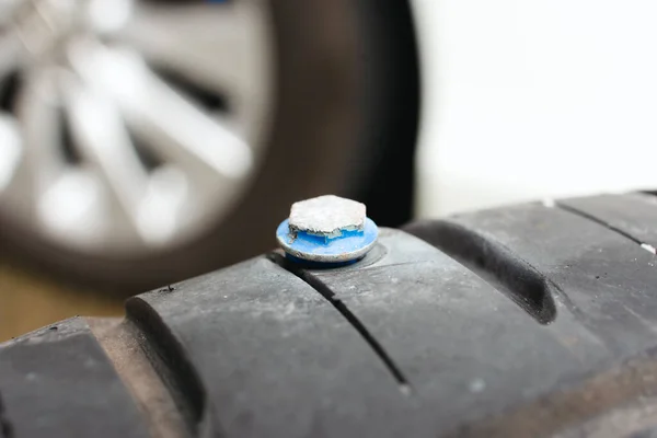 Close up a car tire punctured with metal screws to tire, sharp screws puncture into the side of the car tire. Automotive concept