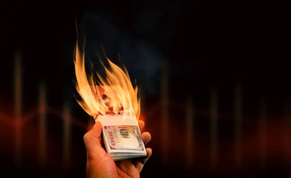 Burning money in hand on a dark background with copy space for text, dollar banknotes with fire blazing in hand. Financial or currency crisis concept