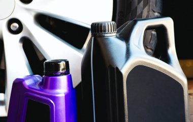 Motor yağı galonu ve arka planda gri bir araba tekerleği olan motor yağı şişesi, araba bakım konsepti.
