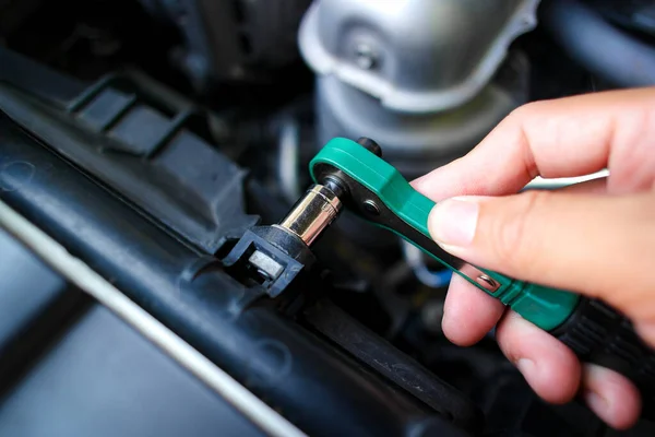Car mechanic hand tighten nuts with small socket wrench for repairing car radiator , car tools concept