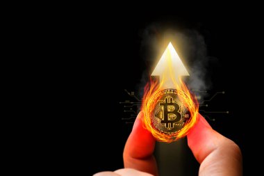 Bitcoin veya kripto para birimi fiyatta önemli bir artışa tanık oldu. Arkaplanda yukarı doğru ok çizelgesi olan alevlerle altın sikkeler tutarak..