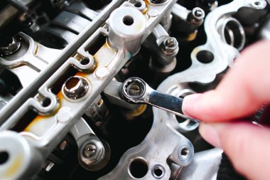 Araba tamircisi, anahtarlı araba motoru valflerini kontrol ediyor ve ayarlıyor.