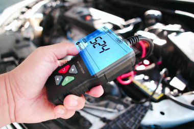 Araba teknisyeni araba tamirhanesinde pilli soğuk aküyü kontrol ediyor. Araba bakım servisi konsepti.