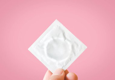 Dünya AIDS Günü konsepti, pembe arka planı olan bir el sıkışma prezervatifi.