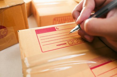 Mal teslimatı kavramı. İnsan eli, müşteriye teslim etmek için bir karton kutuya adres yazar.