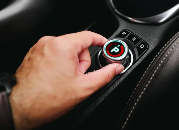 Stock image Driver hand turning a rotary gear shift dial on the dashboard of an EV car or electric vehicle , P Parking gear position , electric car technology concept