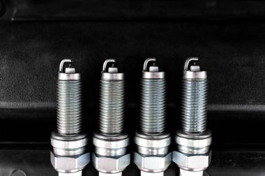 Otomobil Bujileri, dört yeni iridyum bujisi koyu bir arka planda hizalanmış. DIY motor tamiri