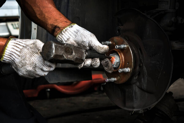 Ремонт валов автомобиля автомехаником. удаление гаек вала привода автомобиля для ремонта подвески автомобиля.