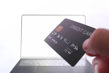 Bilgisayarın önünde elinde bulunan kredi kartı ile çevrimiçi ödeme, güvenli dijital işlem.