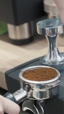 Espresso hazırlamak için portafilterde kahve dolduran bir baristanın yakın çekimi. Profesyonel kahve yapımında önemli bir adım..