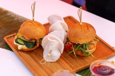 Ahşap masada taze lezzetli ızgara burgerler. Sokak yemekleri festivali.