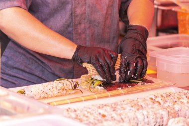 Şef açık mutfakta suşi pişiriyor. Sokak yemekleri festivali.