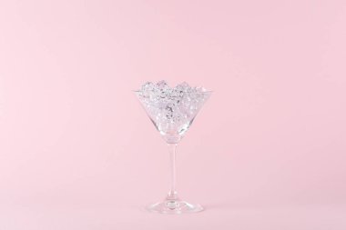 Pembe arka planda elmaslarla dolu martini bardağı. Yaratıcı asgari parti konsepti.