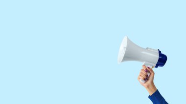 Megaphone in woman hand on blue background. Creative announcement concept. clipart