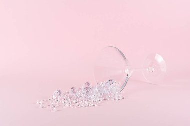 Pastel pembe arka planda elmaslarla martini bardağından yapılmış yaratıcı bir düzen. Asgari parti konsepti.