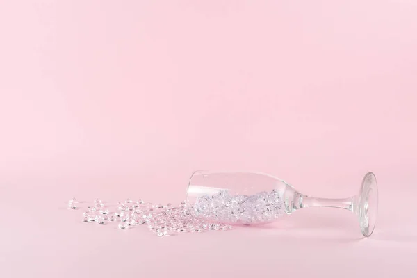 洒了钻石在粉色背景上的酒杯 创造性的最小党的概念 — 图库照片
