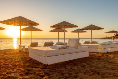 Gün batımında şemsiyeli tropik plaj. Turizm ve seyahat.