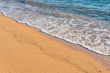 Kumsalda köpüklü deniz dalgası.