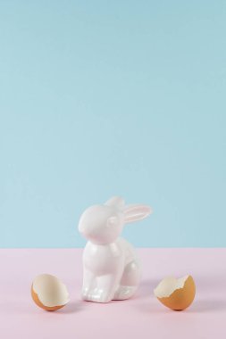 Paskalya tavşanı ya da yumurta kabuğu kırılmış bir tavşan. Minimum pastel pembe ve mavi Paskalya bayramı konsepti.