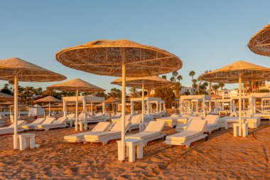 Günbatımında şemsiyeli tropik plaj manzarası. Tatil ve seyahat kavramı.