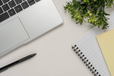 Boş defter, dizüstü bilgisayar ve diğer ofis malzemeleriyle dolu beyaz ofis masası. Kopyalama alanı olan üst görünüm.