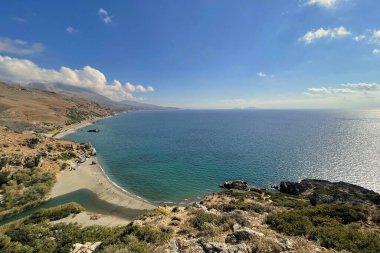 Girit adasında dağları olan Preveli palmiye plajı ve nehir manzarası.