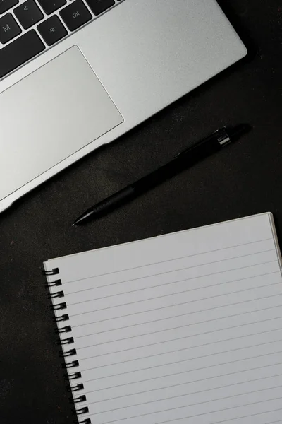 stock image Workspace with blank notebook and laptop on black background. Top view with copy space.