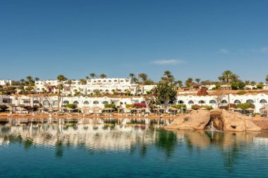 Beyaz binalar ve Kızıl Deniz kıyısında bir dinlenme alanı..