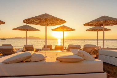 Günbatımında şemsiyeli tropik plaj manzarası. Tatil ve seyahat kavramı.