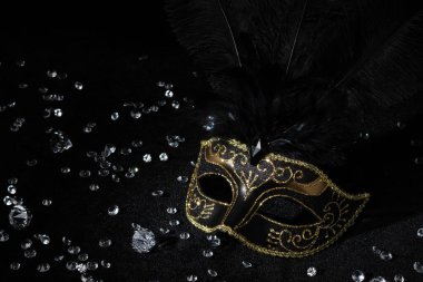 Siyah zemin üzerinde değerli taşlar olan altın maskeli balo.