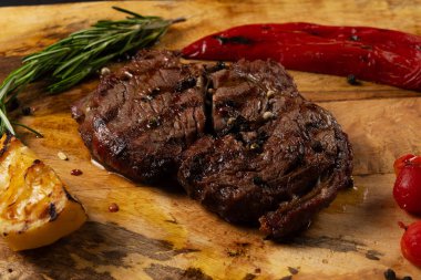 Izgara Pirzola Siyah Angus ahşap arka planda biber ve otlarla servis edilir..