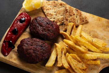 Tahtaya kızarmış patates, biber, pide ve yoğurt sosu ile kıyma yapılmış XL biftek köftesi..