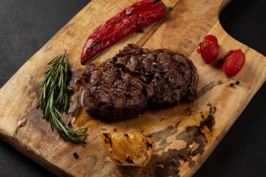 Lezzetli Pirzola Siyah Angus ahşap tahtada biber ve otlarla servis edilir..