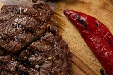 Yakın plan ızgara kaburga gözü Black Angus ahşap arka planda biber ve otlarla servis edilir..