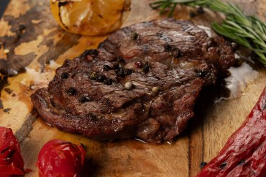 Yakın plan ızgara kaburga gözü Black Angus ahşap arka planda biber ve otlarla servis edilir..