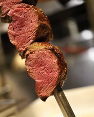 Picanha mangal kömüründe kızartılmış biftek. Bıçak şişi kesiyor. Churrascaria restoranında Brezilya eti